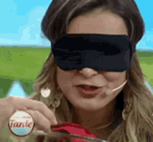 a woman wearing a blindfold and a microphone is holding a knife and fork .