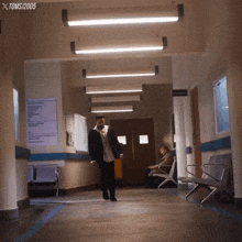 a man in a suit walks down a hallway with toms / 2005 on the bottom
