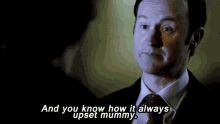 a man in a suit and tie is talking to another man in a dark room .
