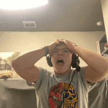 a man wearing headphones and a t-shirt with a picture of a boxing glove on it holds his head