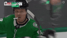 a hockey player wearing a green jersey and a black helmet with the word stars on the top