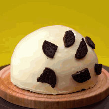 a cake with oreos on top of it on a wooden cutting board