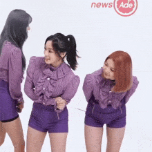 three women in purple shirts and shorts are standing next to each other with a news ade logo behind them