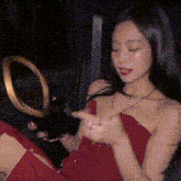 a woman in a red dress is sitting in a car with her eyes closed and looking at her phone .