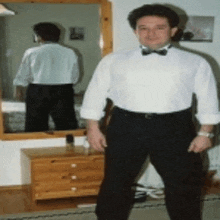 a man in a white shirt and black pants is standing in front of a mirror