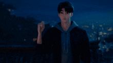 a man in a black jacket stands in front of a city at night