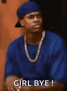 a man in a blue shirt and hat is sitting at a table with his hand on his heart .