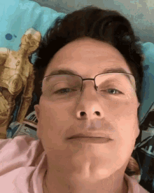 a man wearing glasses and a pink shirt is laying on a star wars pillow