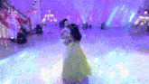 a man and a woman are dancing on a stage with purple lights