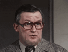 a man with glasses and a beard looks to the side