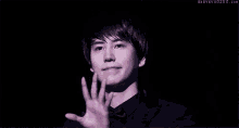 a young man is waving his hand in the dark .
