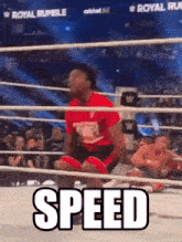 a man in a red shirt is kneeling in a wrestling ring with the words speed written on it .