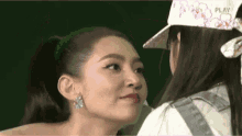 two women are touching each other 's faces while wearing hats .
