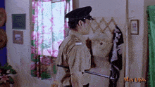 a man in a police uniform is holding a stick in a room with man laksa written on the bottom