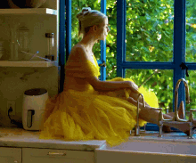 a woman in a yellow dress is sitting on a kitchen counter