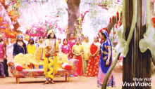 a group of people dressed in traditional costumes are standing in front of a tree .