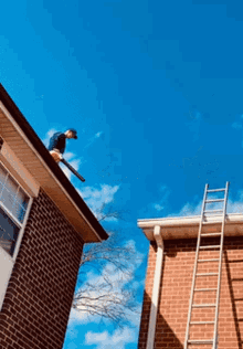 a man is standing on the roof of a brick house with a ladder