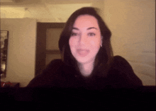 a woman in a black shirt is smiling in a blurry photo