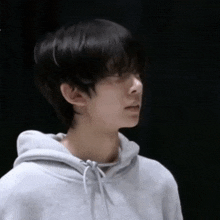 a young man wearing a grey hoodie looks to the side