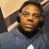 a close up of a person wearing headphones and a blue hoodie .