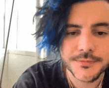 a man with blue hair and a beard is wearing a black shirt