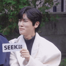 a man in a white coat is holding a seek sign