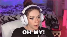 a woman wearing headphones is sitting in a chair and making a surprised face .