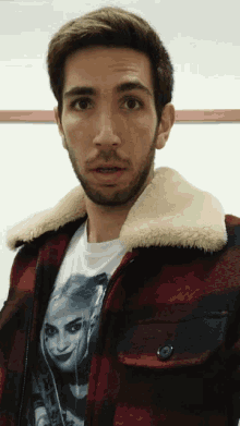 a man wearing a plaid jacket and a t-shirt with a picture of harley quinn on it