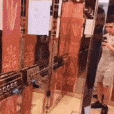 a man is standing in an elevator taking a picture of himself in the mirror .