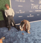 two men on a blue carpet with a sign that says " the bear "
