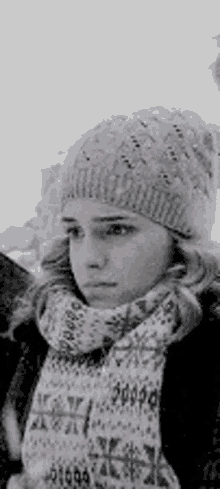 a woman wearing a hat and scarf is looking at the camera .