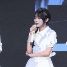 a girl in a white dress is holding a microphone in her hand