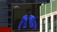 a man in a blue shirt and tie stands in front of a large screen that says ' am 2010 ' on it