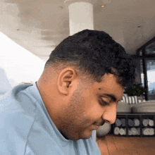 a man with a beard and a blue shirt looks down