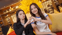 two women are making a heart shape with their hands and one is wearing a shirt that says chez vous