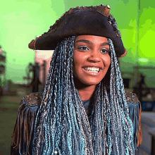 a woman with blue braids and a pirate hat smiles
