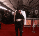 a man standing on a red carpet with a sign that says muscles and pain relief