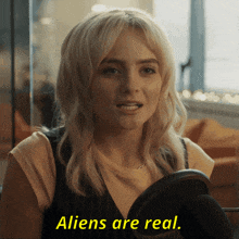 a woman says aliens are real while holding a mirror