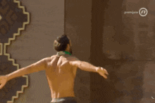 a shirtless man with his arms outstretched in front of a wall that says premiera on it