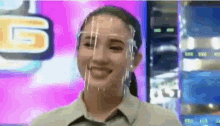 a woman wearing a face shield is smiling and making a funny face .