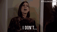 a woman in a floral dress is standing in front of a window and saying `` hate it '' .