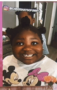 a girl wearing a mickey mouse shirt is smiling