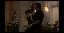 a man in a suit sits next to another man in a suit on a balcony