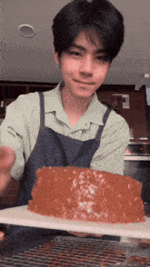 a young man in an apron is holding a piece of cake