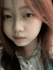 a close up of a girl 's face with red hair and a striped shirt