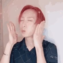 a young man with red hair is making a funny face with his hands .