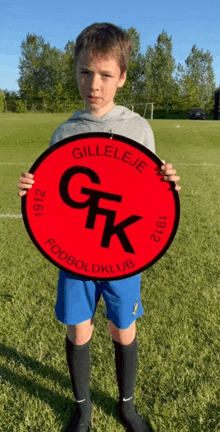 a young boy is holding a red sign that says gk