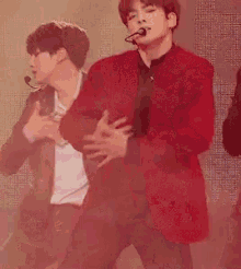 a man in a red jacket is dancing on stage .