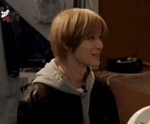 a man with long blonde hair is wearing a black jacket