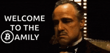 a man sitting in front of a sign that says welcome to the family